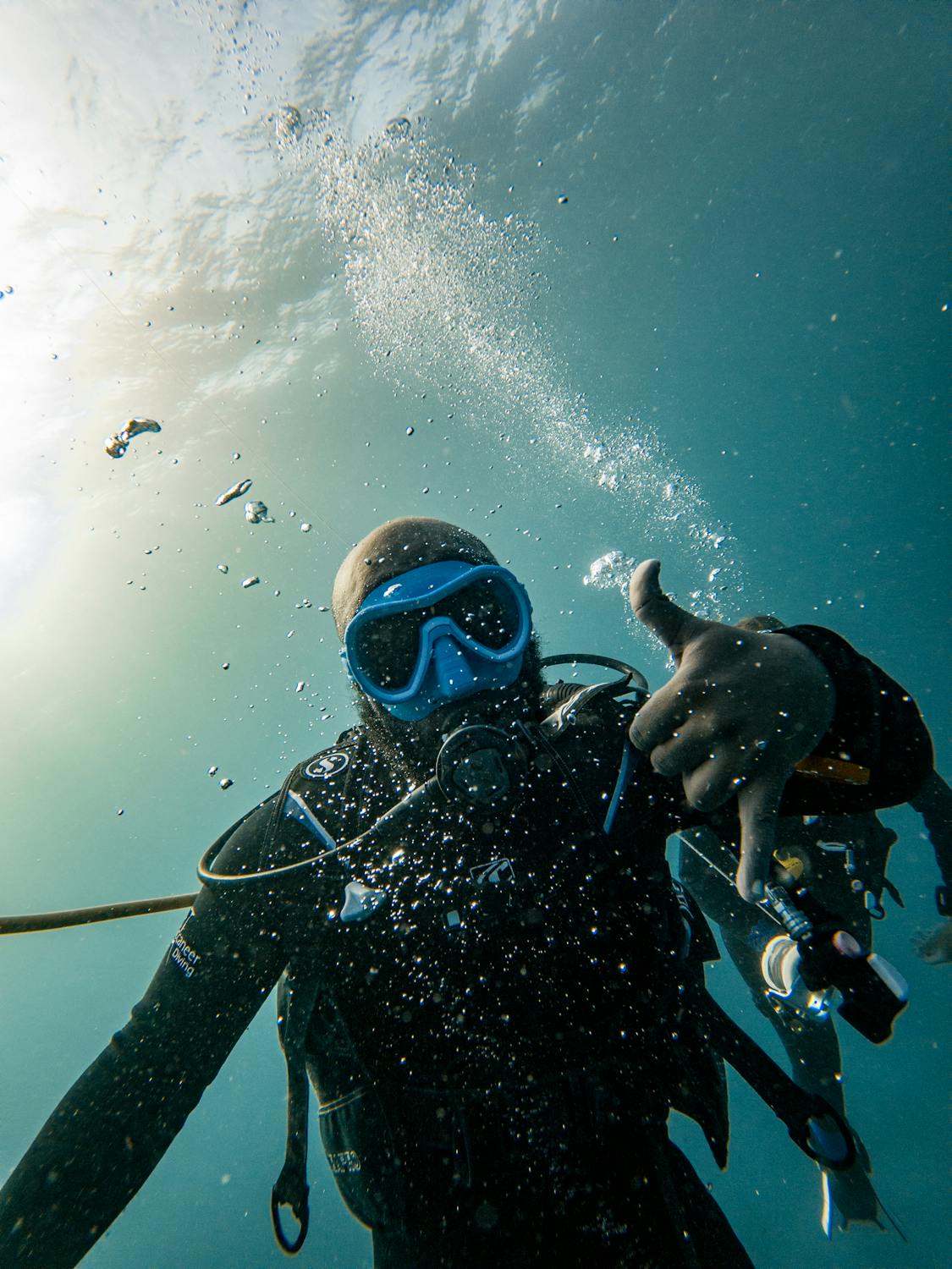 Scuba diver giving OK hand signal underwater surrounded by bubbles
